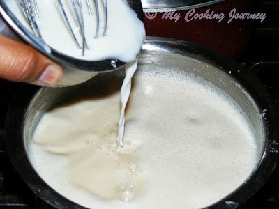 Adding corn flour mixture to boiling milk Adding corn flour mixture to boiling milk