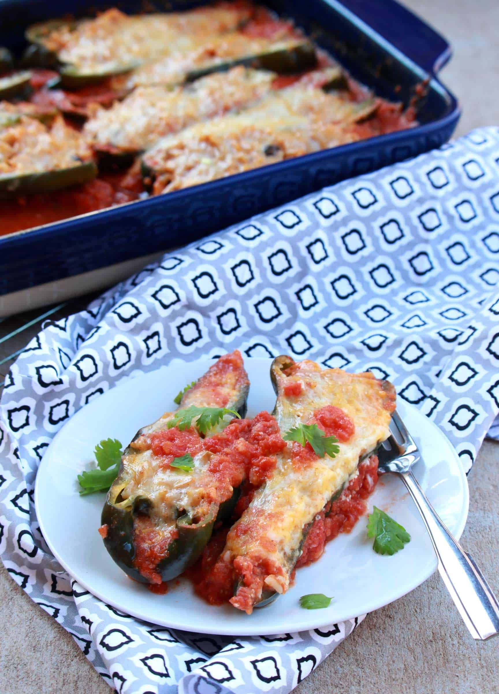 Stuffed Poblanos | Poblano peppers stuffed with beans and rice two stuffed peppers on a plate with more in a casserole