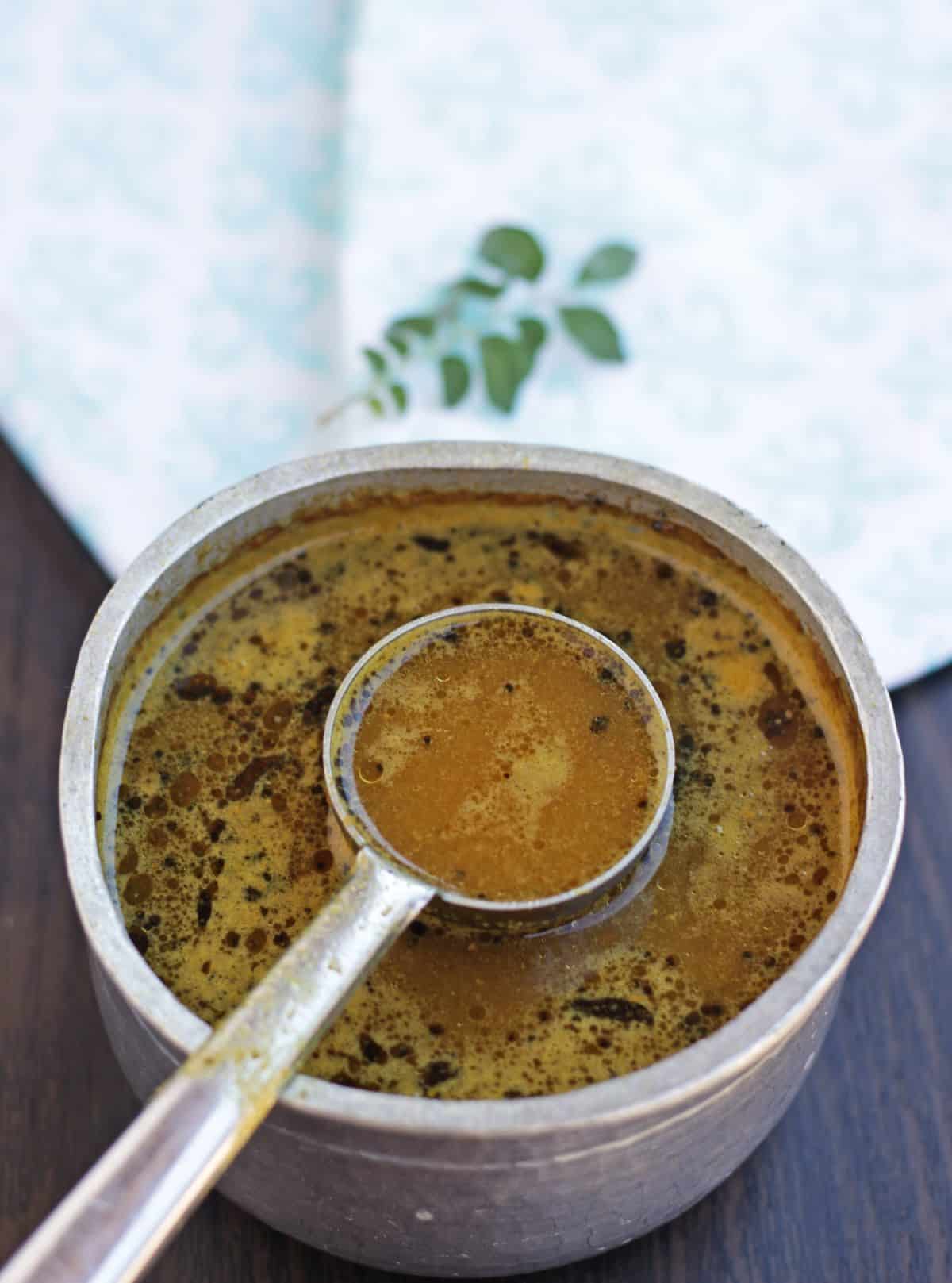 rasam in a vessel with ladle inserted