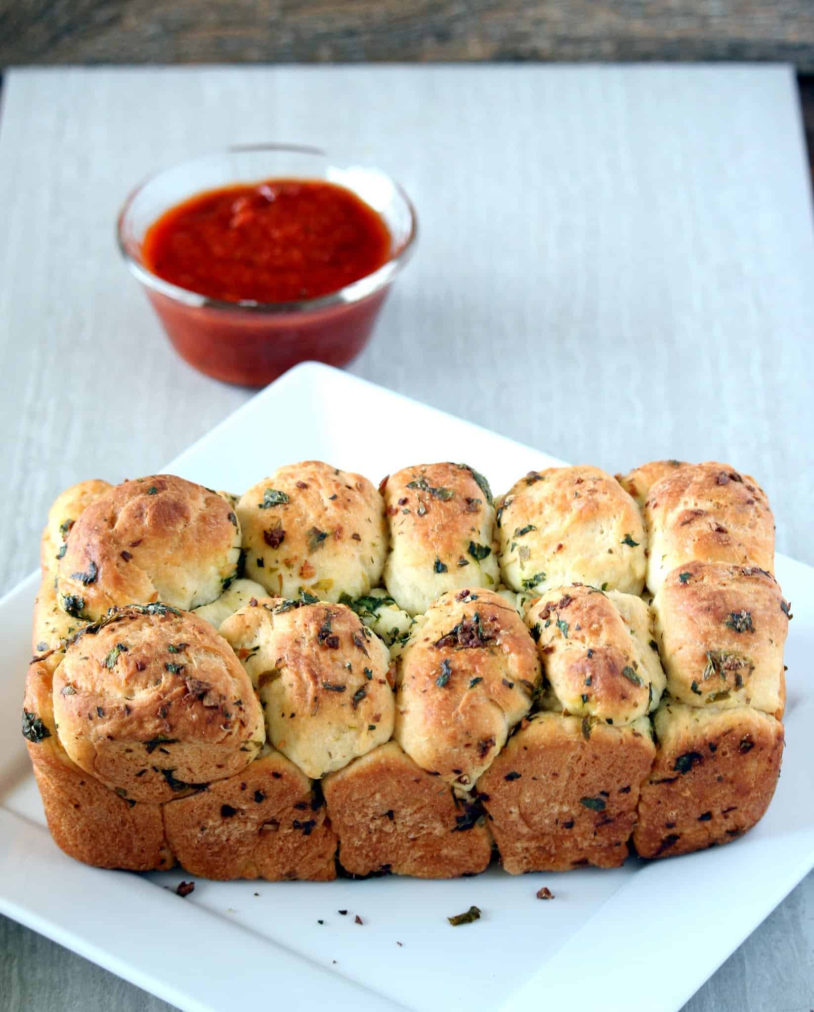 loaf of garlic bread with sauce in the background