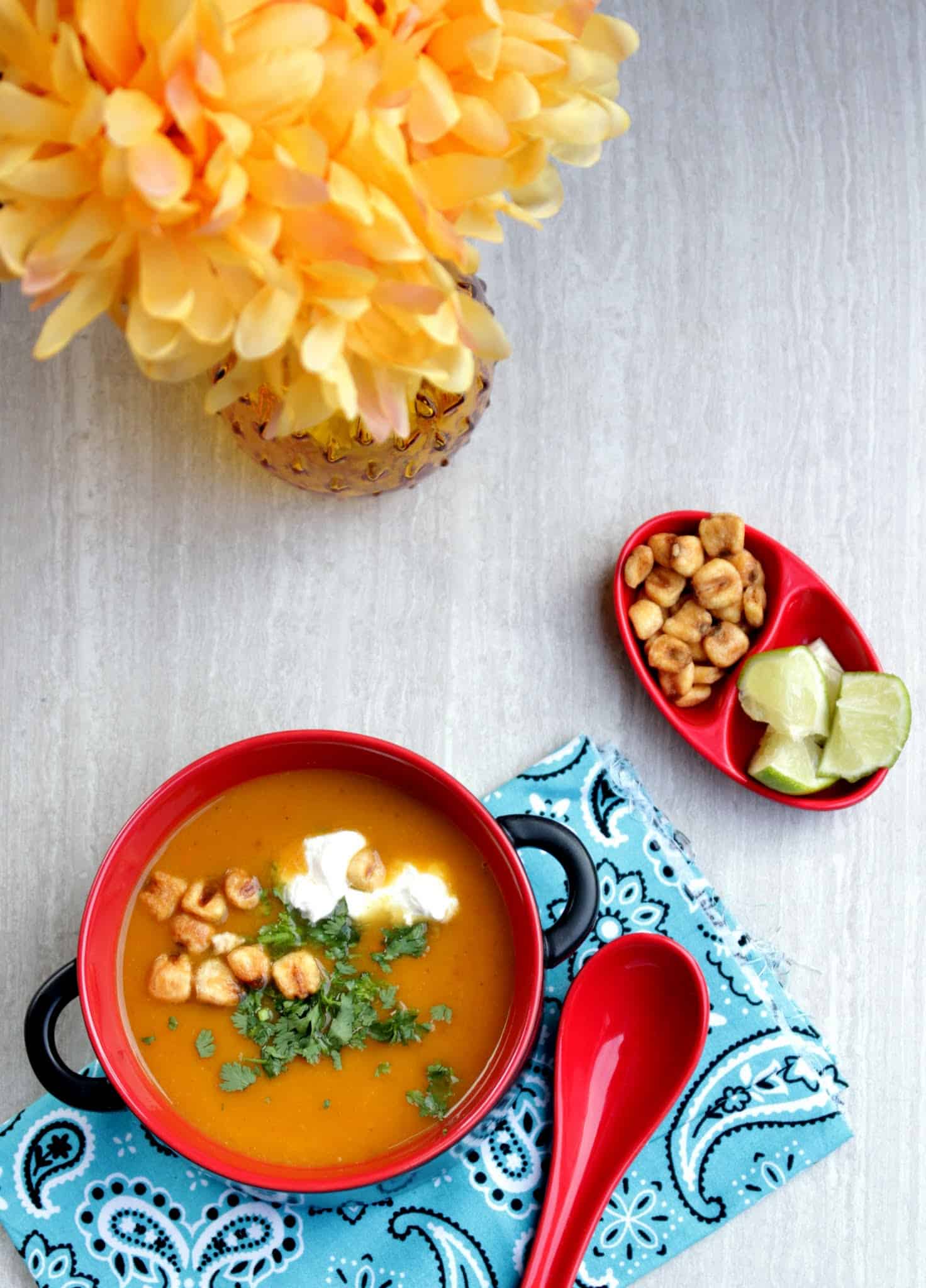 Roasted Butternut Squash Soup served in a red bowl with spoon and also with lemon