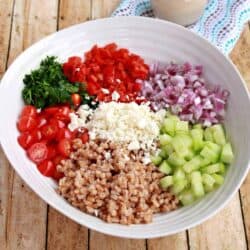 salad bowl with different vegetables and cheese and farro