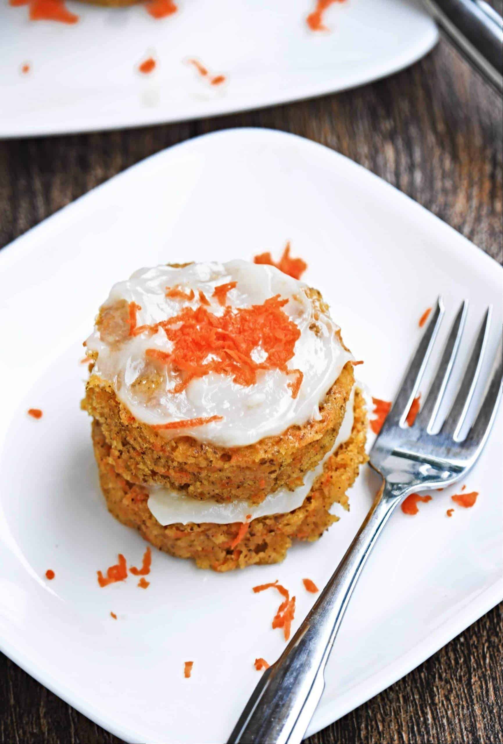 Single carrot cake serving with frosting and grated carrots on top
