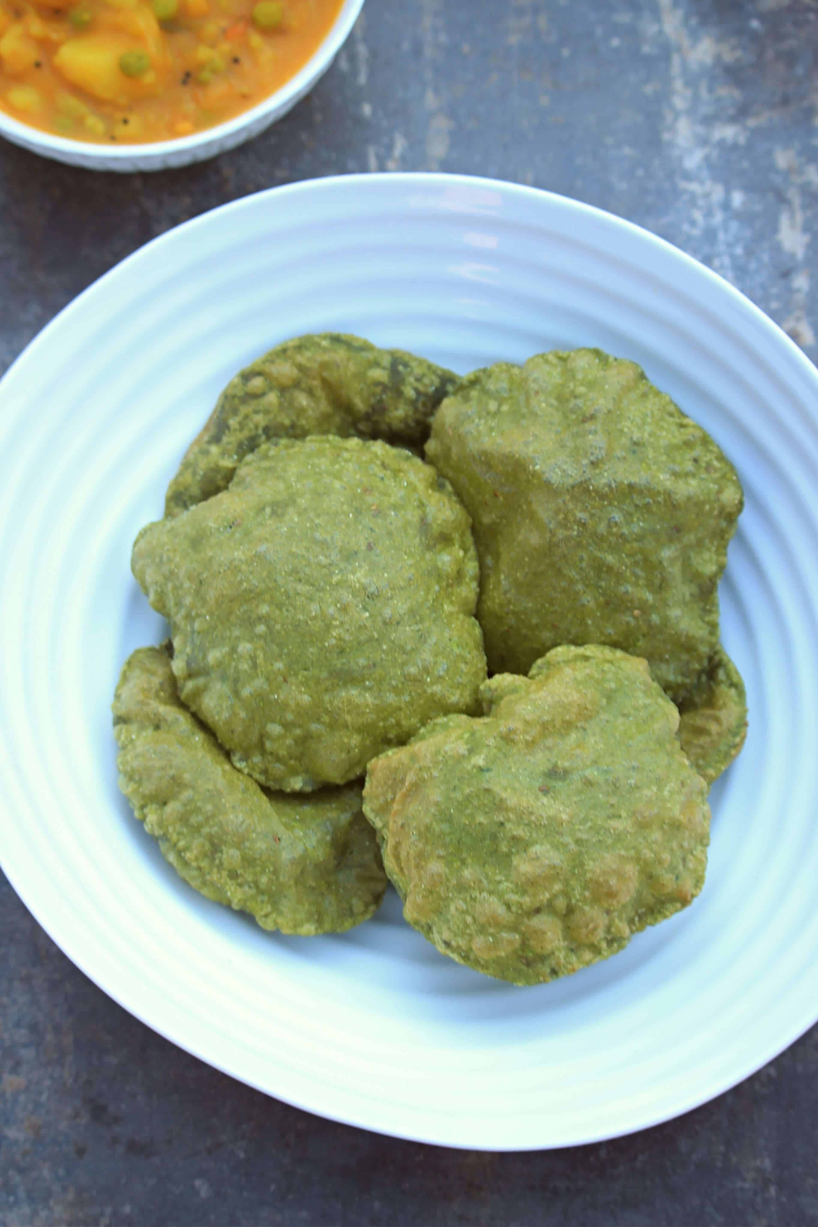 Palak Puri | Spinach Poori | Deep Fried Spinach Flatbread spinach poori in a white dish