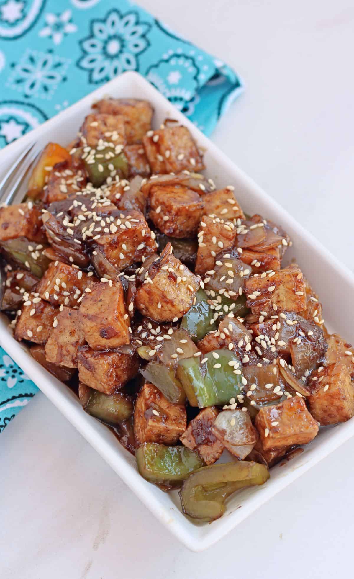 Tofu stir fry with onion and bell pepper in a white plate