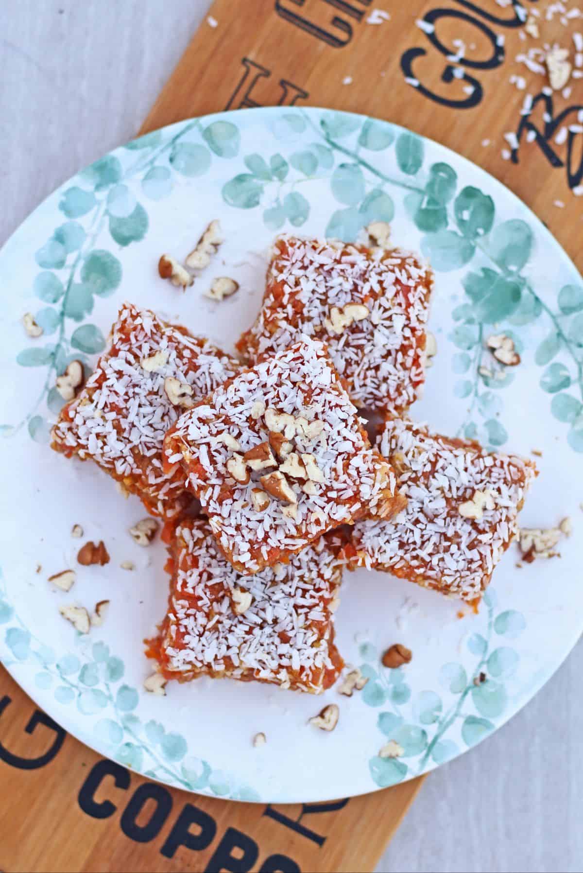 Carrot and walnut bars in a plate garnished with coconut and nuts