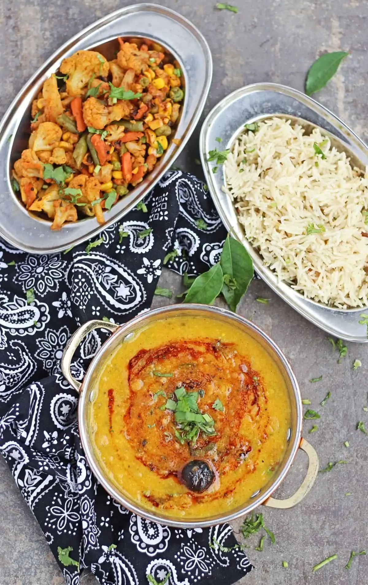 Mango toor dal in a bowl with rice and vegetables in background