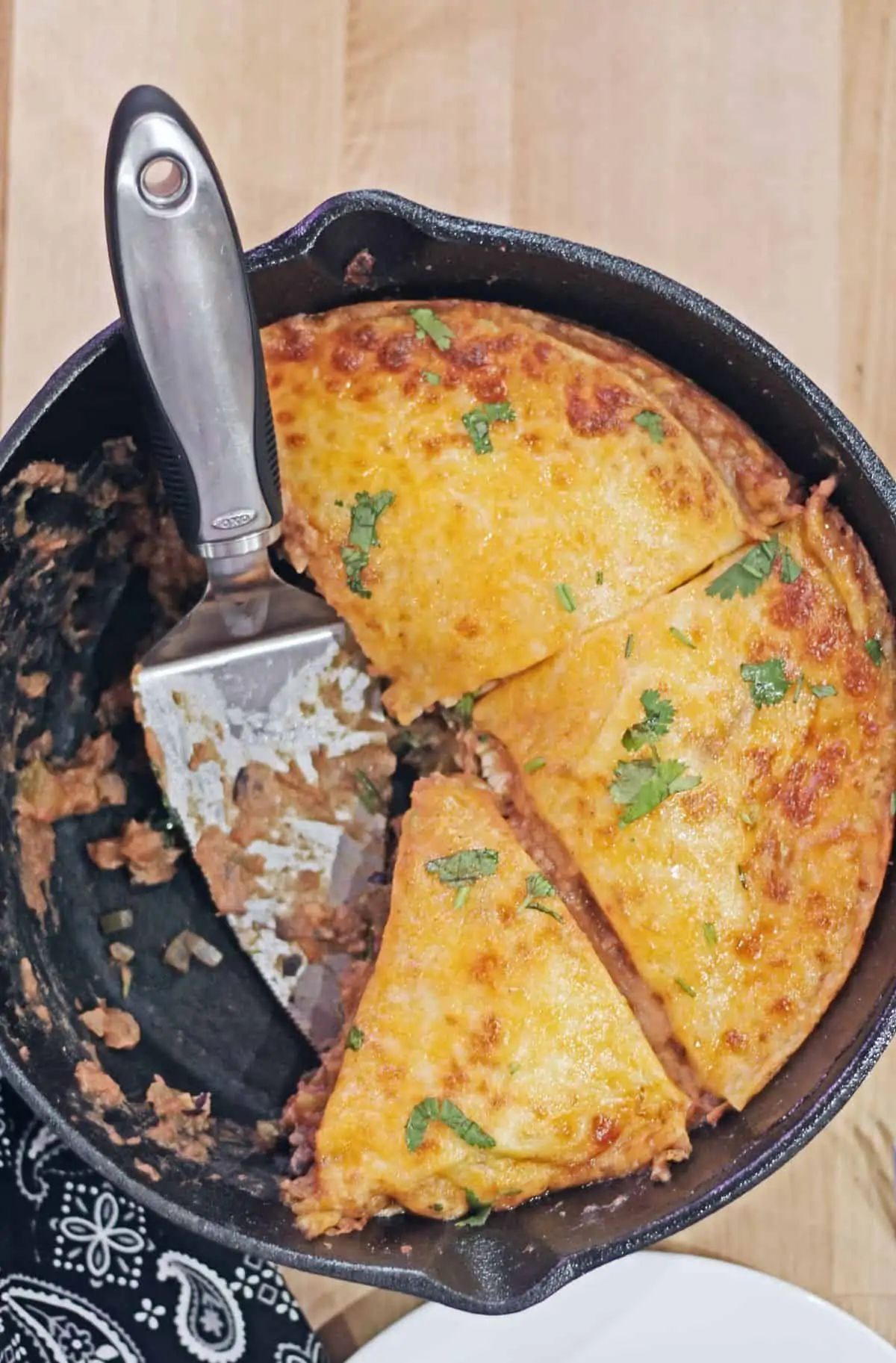 sliced tortilla pie with a serving spoon on a cast iron skillet