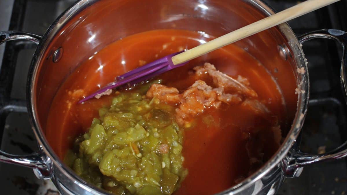 enchilada sauce, refried beans and green chiles in a sauce pan