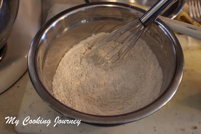Mixing baking soda and powder in a bowl with hand mixture.