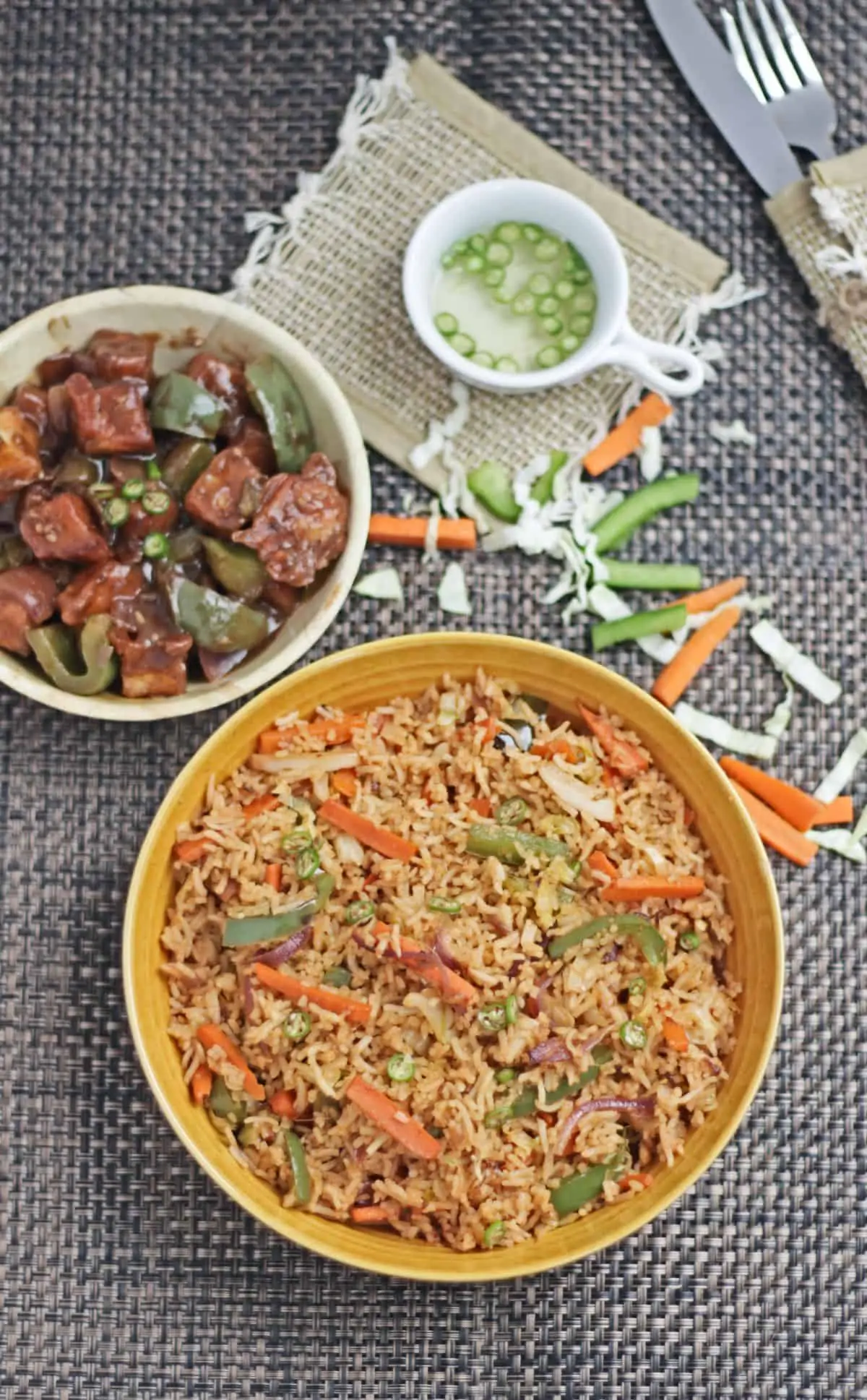 Fried rice with mixed vegetables and fried tofu and vegetables in the background