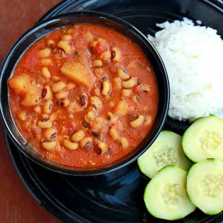 Lobia and Aloo Subzi in a black bowl with rice and cucumber on the side - Featured Image