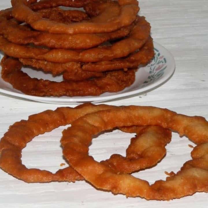 Sel Roti Stacked in a plate with couple next to them - Featured Image