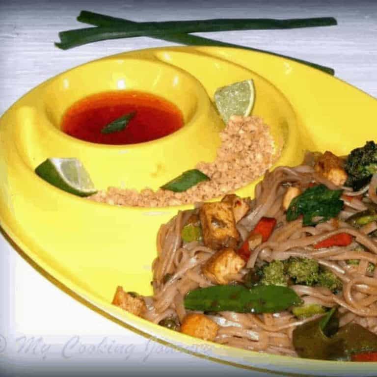 Pad Thai in a plate with sauce and peanuts on the side - Feature Image